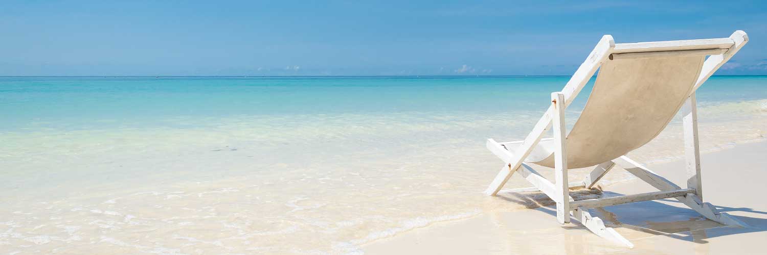 a beach chair sitting empty on a beautiful sandy beach at the foot of a calm ocean view