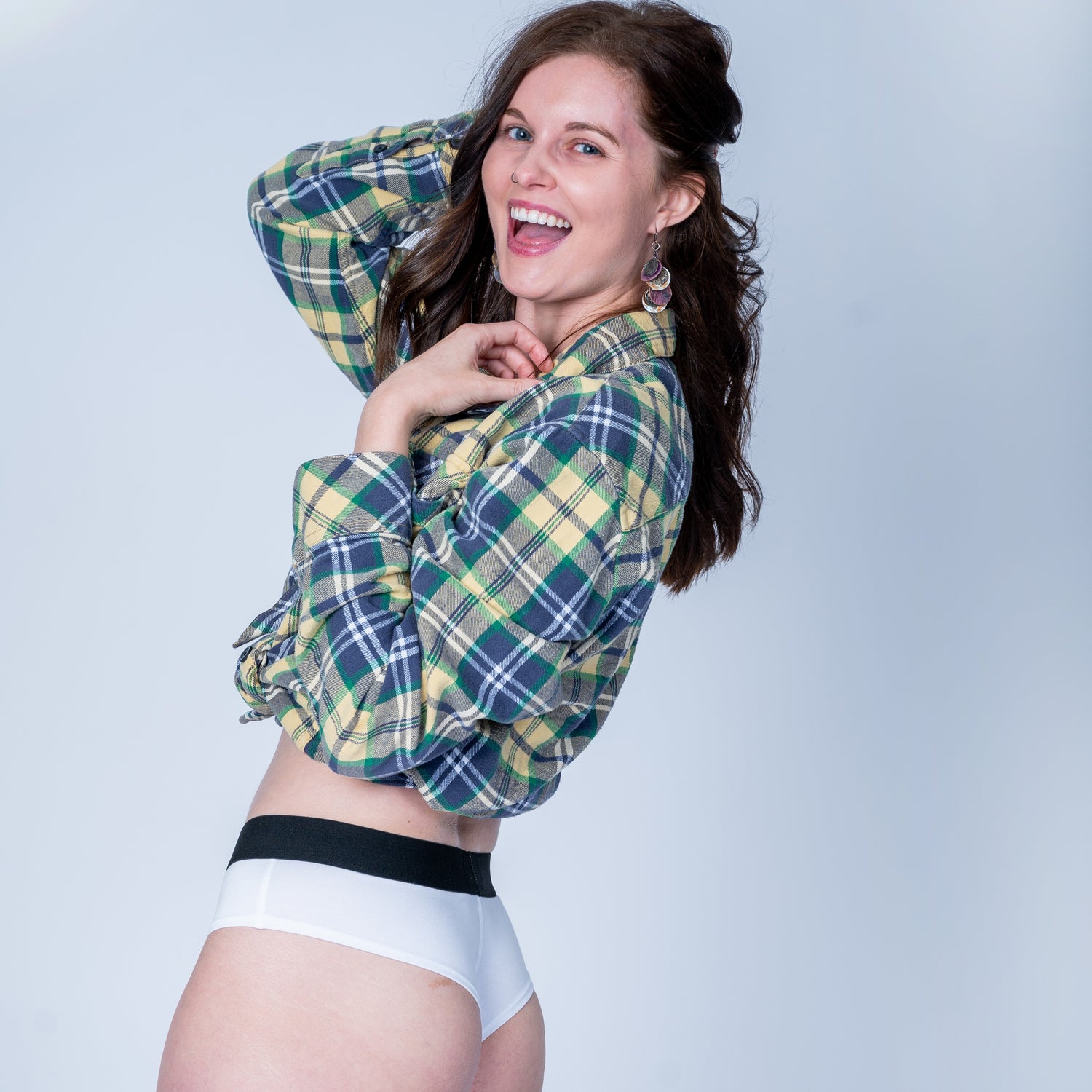 model in white do and dare cheeky underwear and a plaid flannel smiling big at camera