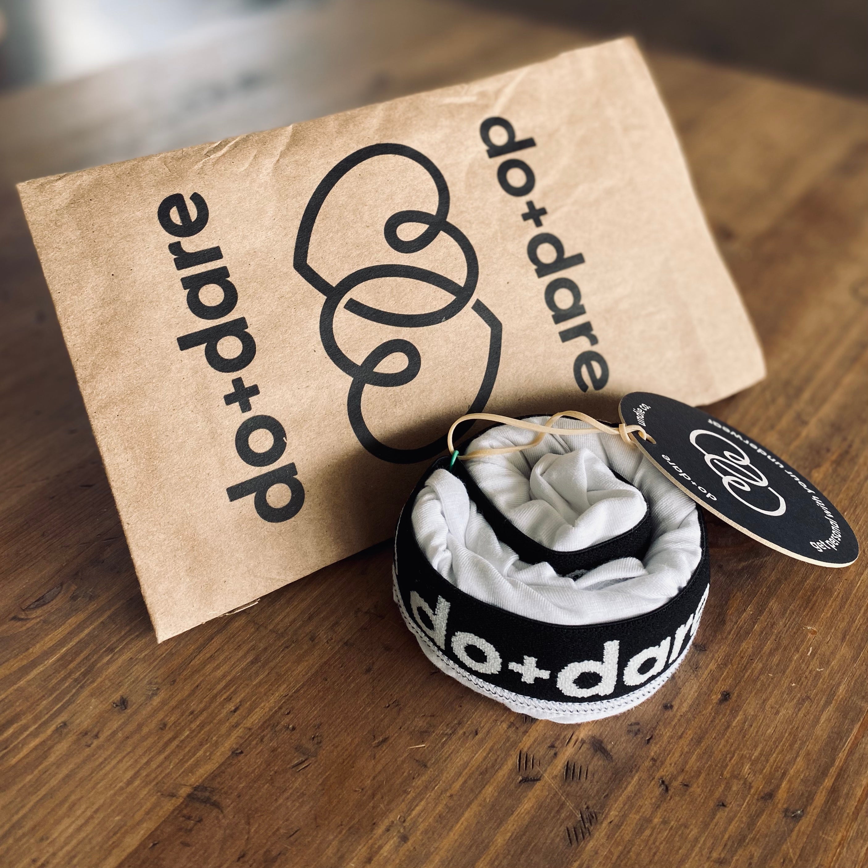 underwear rolled into a puck in front of a brown paper recyclable mailer mailer with do and dare undie co logo on it